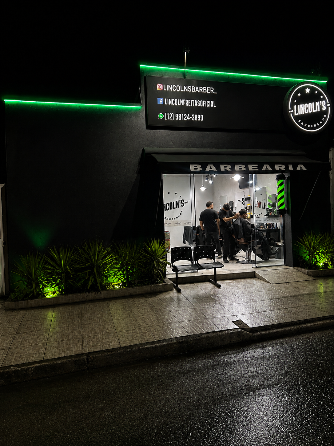 Fachada da Lincoln's Barbershop iluminada em verde neon à noite